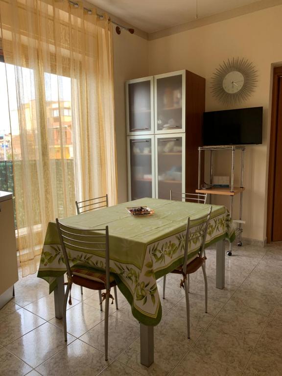 een eetkamer met een tafel met stoelen en een televisie bij Playa Apartment in Catania