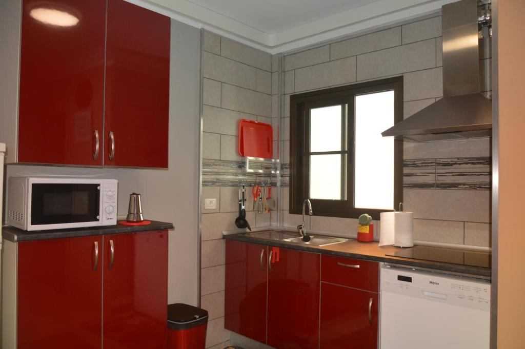 - une cuisine équipée de placards rouges et d'un four micro-ondes dans l'établissement Calle Real, à San Sebastián de la Gomera