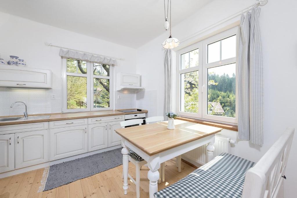 a kitchen with white cabinets and a wooden table at Baráček in Janov nad Nisou