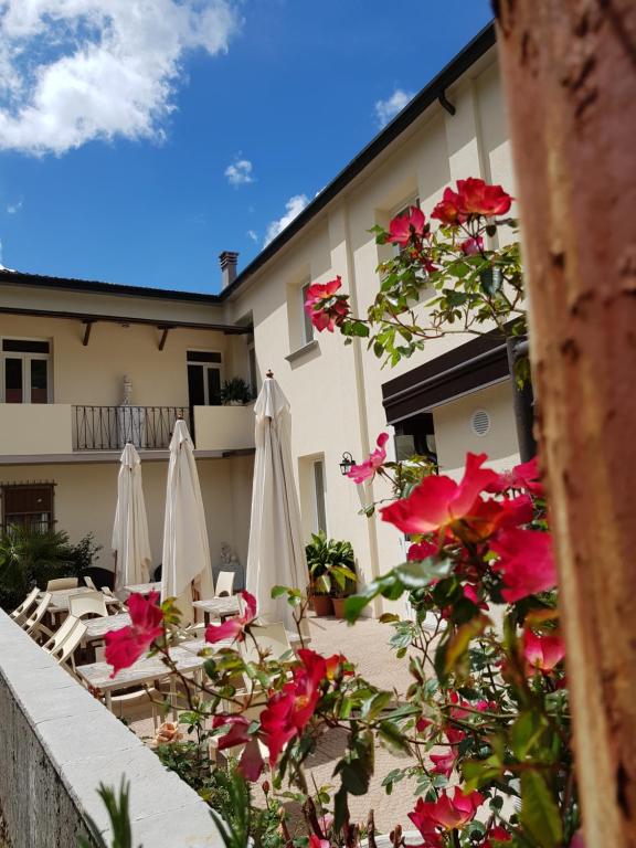 a patio with white umbrellas and flowers in front of a building at Locanda Elena in Equi Terme
