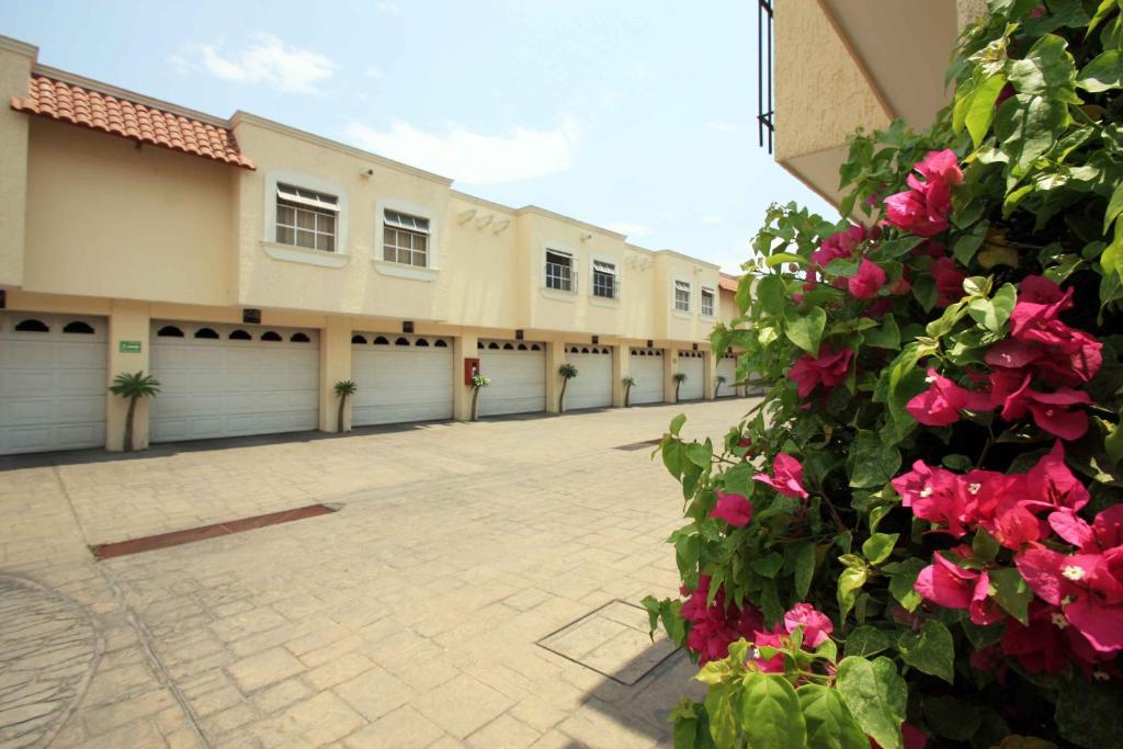a row of garages with pink flowers in a courtyard at Motel Mirage in Guadalajara