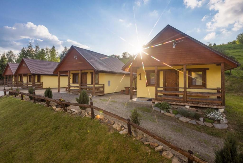 una fila de casas con el sol brillando sobre ellas en Dolina Orła, en Wola Matiaszowa