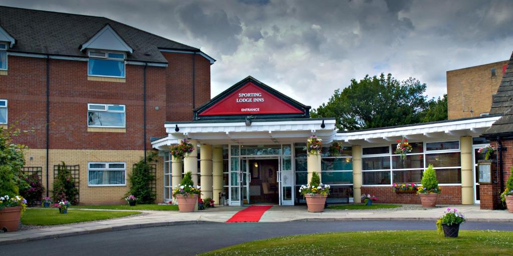 un gran edificio de ladrillo con techo rojo en The Greyhound Hotel, en Leigh