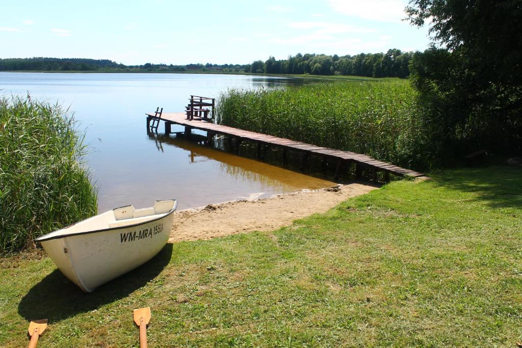 a boat sitting on the grass next to a dock at Bajkowe Mazury Domek Holenderski PLAŻA ŁÓDKI KAJAKI WĘDKOWANIE in Mikołajki