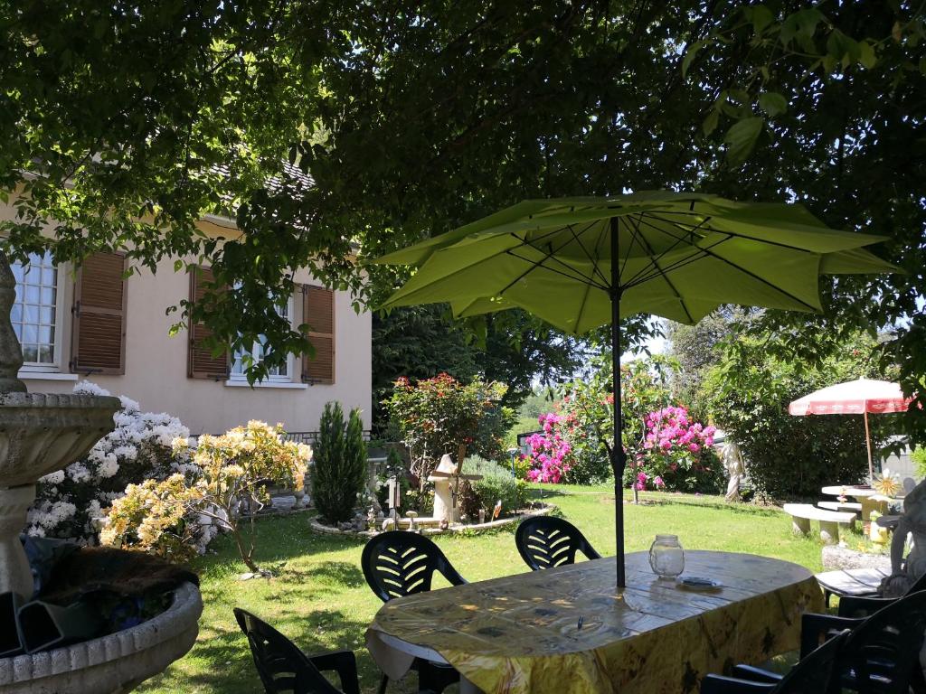 einen Tisch mit einem grünen Regenschirm im Hof in der Unterkunft Au Jardin Fleuri in Secondigny