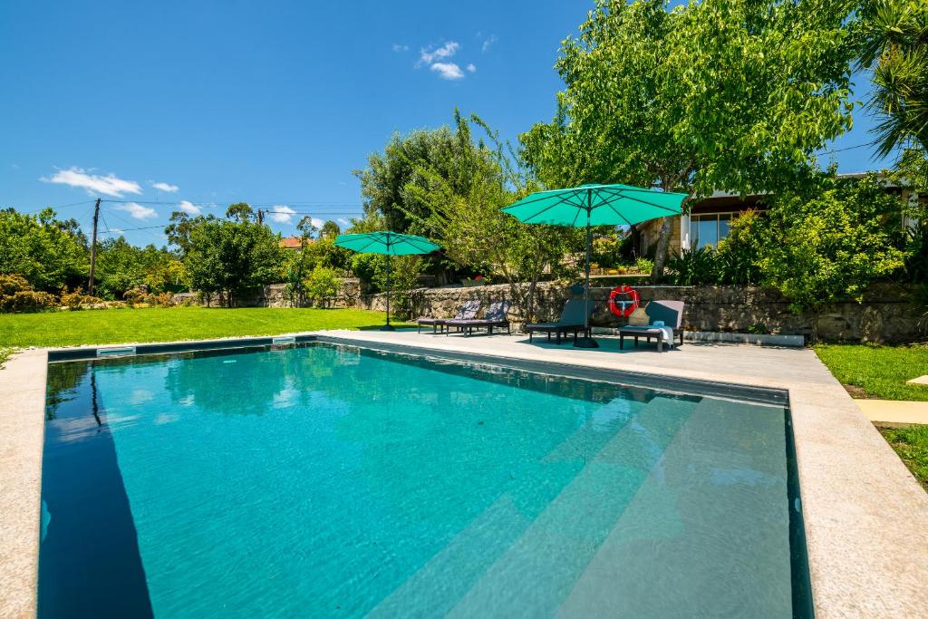 uma piscina com dois guarda-sóis e duas cadeiras em Casa de Campo - Olive House em Areias de Vilar