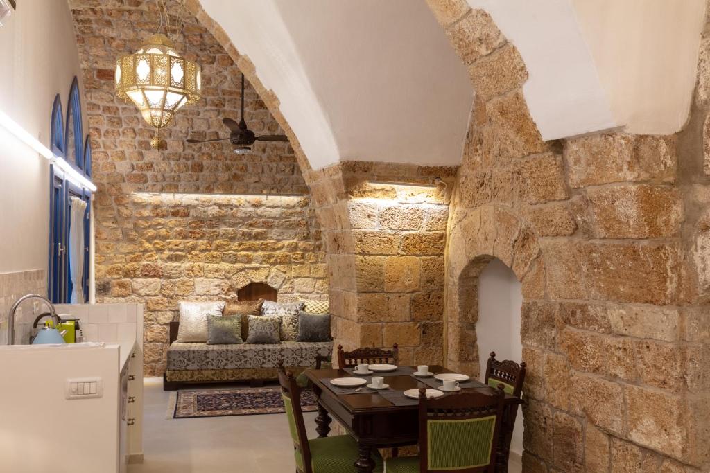 a dining room with a table and a stone wall at Alma in ‘Akko