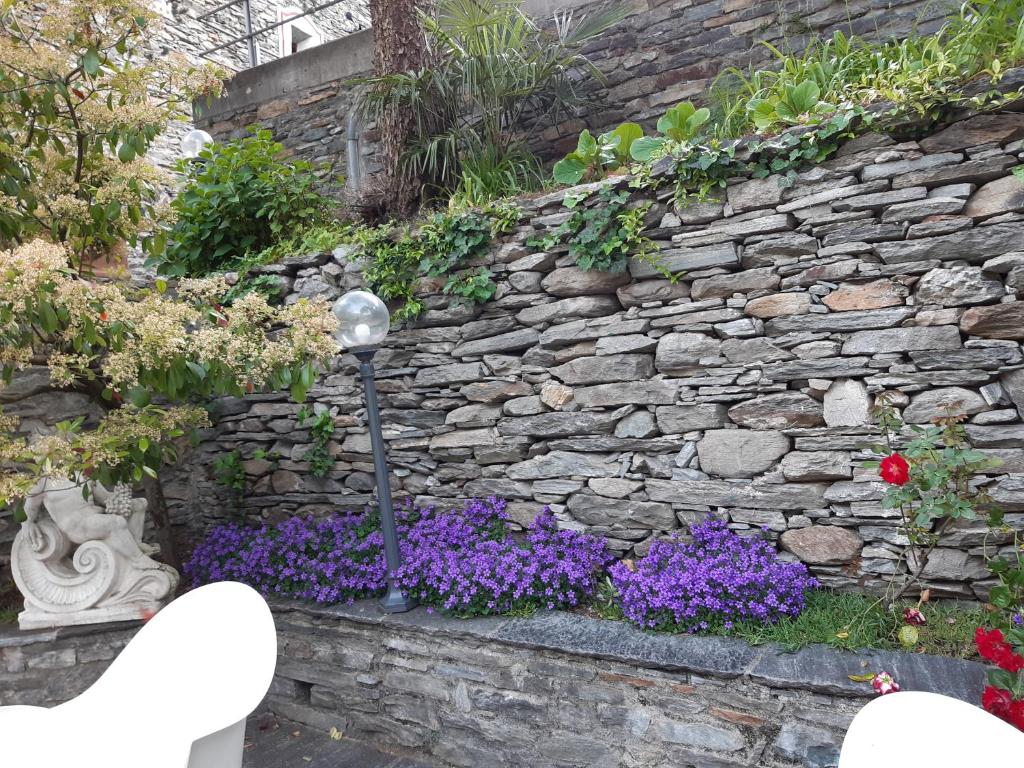 una pared de piedra con flores púrpuras y luz de la calle en Hotel Soazza, en Soazza