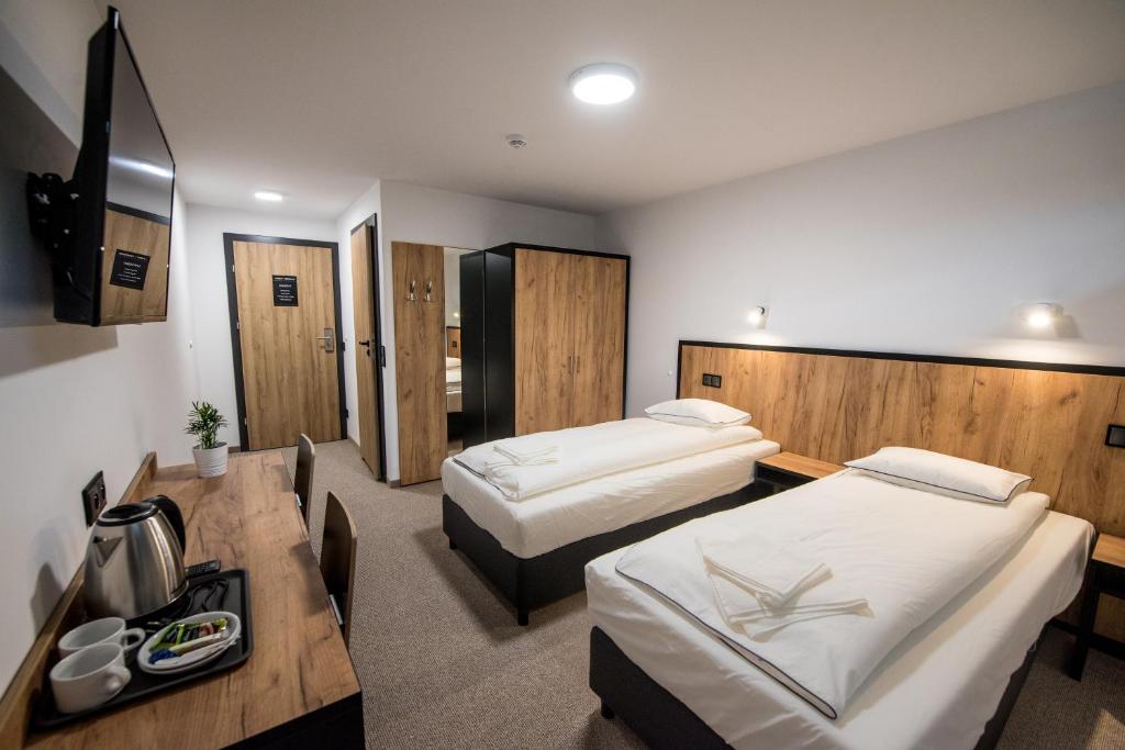 スパワにあるSport Rooms Spałaのベッド2台とデスクが備わるホテルルームです。