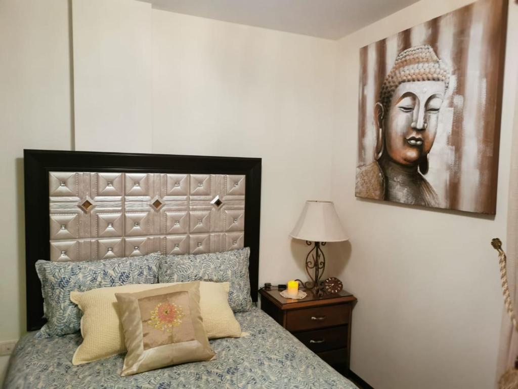 Acogedor y Elegante Estudio cerca al Prado في كوتشابامبا: غرفة نوم مع سرير مع اللوح الأمامي كبير وصورة