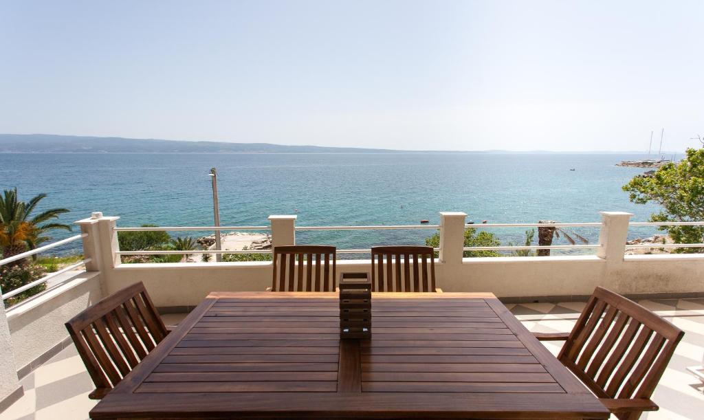 een houten tafel en stoelen op een balkon met uitzicht op de oceaan bij Bella Vista in Jesenice