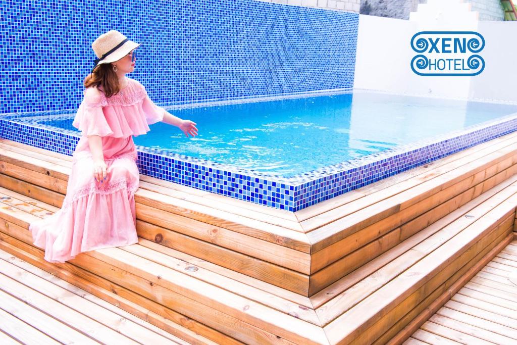 una bambina con un vestito rosa in piedi accanto alla piscina di Xen Midu Hotel Addu City Maldives a Midu