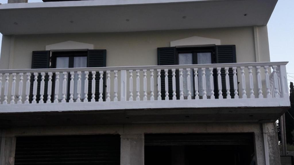 a white balcony on a house with black shutters at STERNES house in Agios Leon