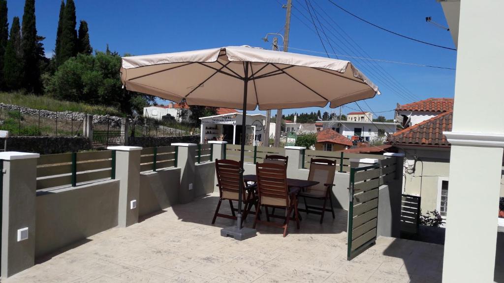 a patio with a table and chairs under an umbrella at STERNES house in Agios Leon