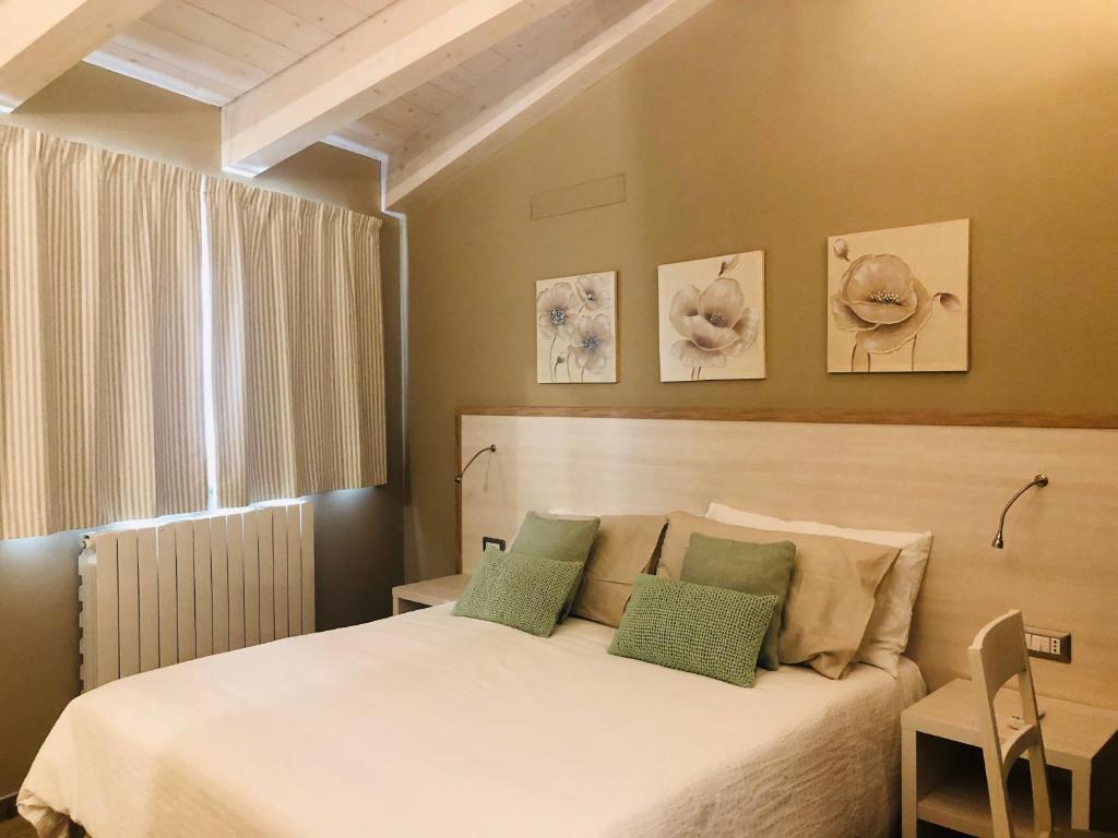 una camera con un letto bianco con due cuscini verdi di La Dimora di via Trieste a Civitanova Marche
