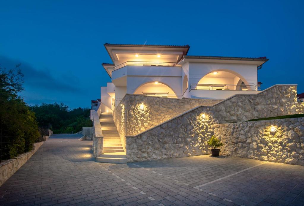 una casa con luces en una pared de piedra por la noche en Apartmani Villa Zora, en Lopar