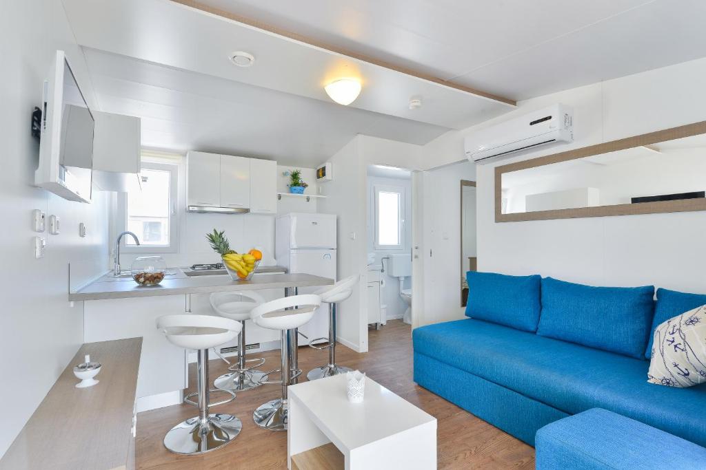 a living room with a blue couch and a kitchen at Mobile house Nord 1 Laguna in Turanj