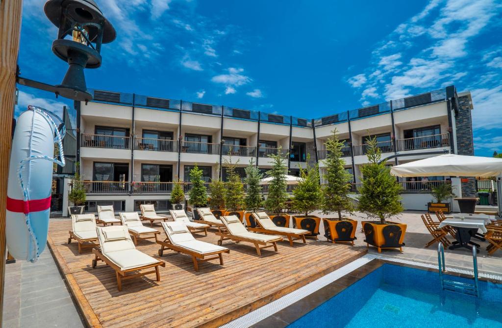 um pátio do hotel com cadeiras e uma piscina em Kosa Otel Çeşme em Cesme