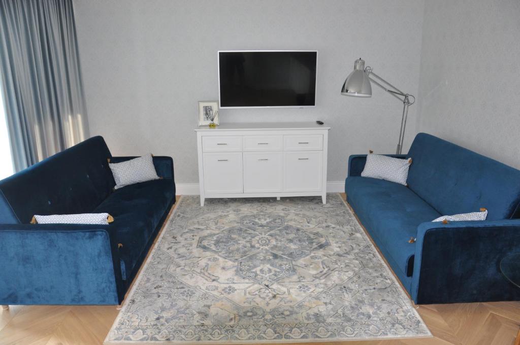 a living room with two blue couches and a tv at Apartament Bello Mechelinki in Mechelinki