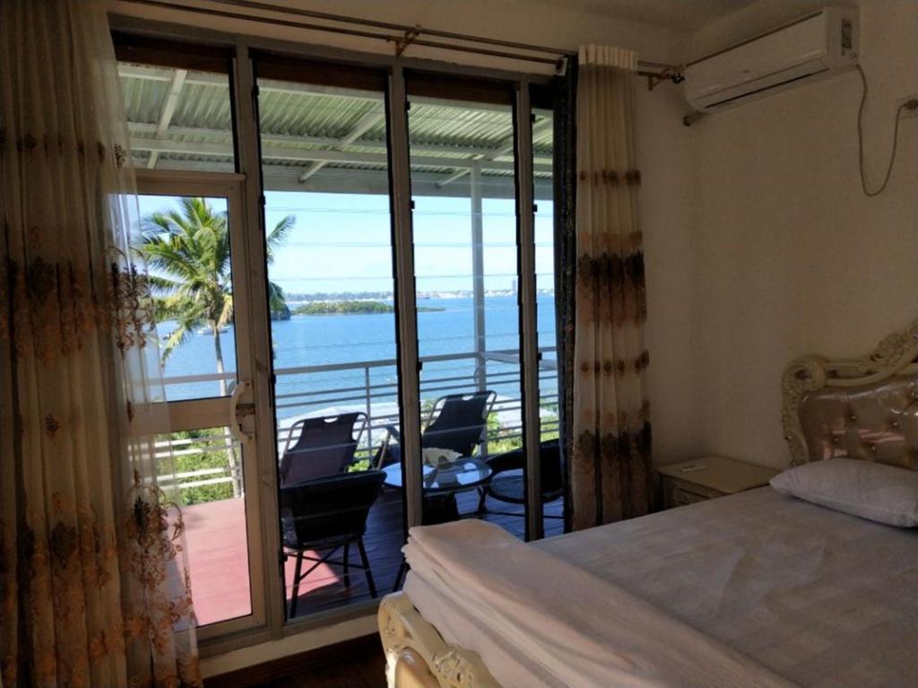 Suva Hideaway Villa في سوفا: غرفة نوم مع سرير وإطلالة على المحيط