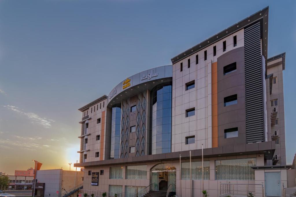 a large building with a sunset in the background at South Hotel Suites in Khamis Mushayt