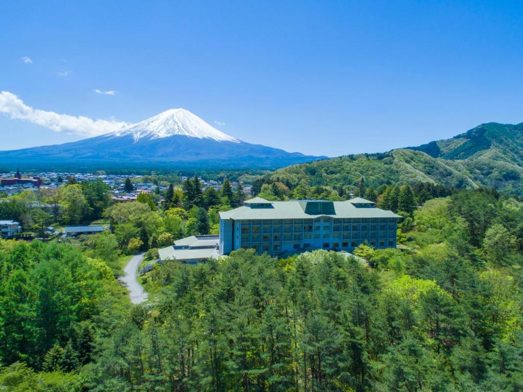 un edificio en una colina con una montaña en el fondo en Fuji View Hotel en Fujikawaguchiko