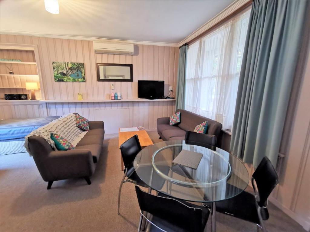 ein Wohnzimmer mit einem Glastisch und Stühlen in der Unterkunft Elm Lodge Bright in Bright