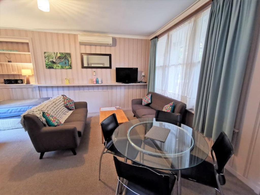a living room with a glass table and chairs at Elm Lodge Bright in Bright