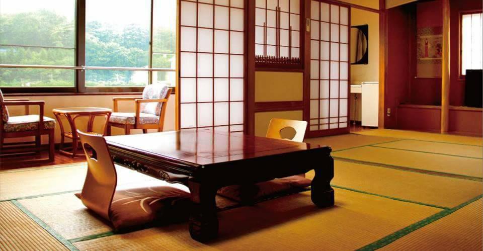 einen Tisch und Stühle in einem Zimmer mit Fenstern in der Unterkunft Oyado Matsubaya in Minakami