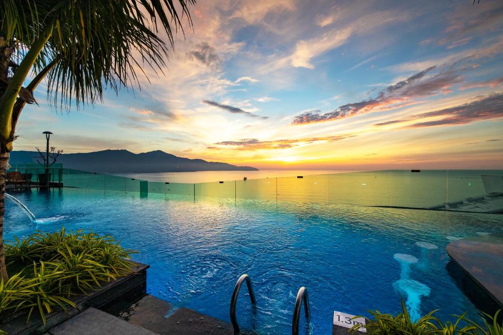 uma piscina com vista para o oceano ao pôr-do-sol em Sala Danang Beach Hotel em Da Nang