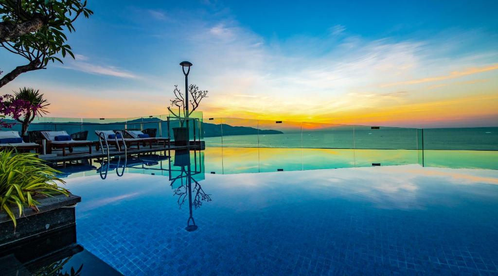 An infinity-style rooftop pool overlooking the sea at sunset.