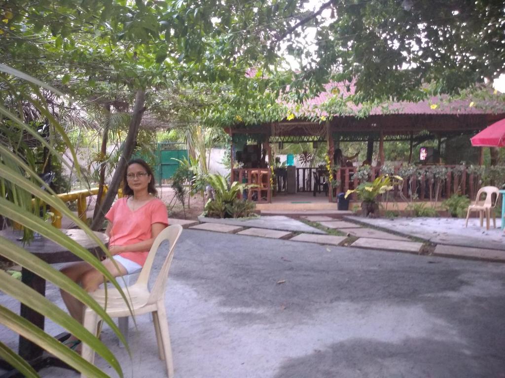 une femme assise sur une chaise sous un arbre dans l'établissement Enna's Place, à Coron