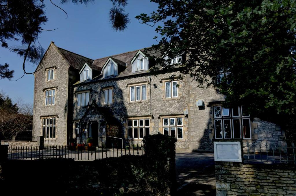 ein großes Steingebäude mit einem Zaun davor in der Unterkunft Stonecross Manor Hotel in Kendal