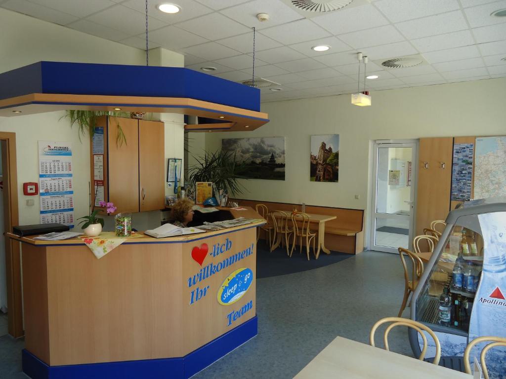 a woman sitting at a counter in a waiting room at Sleep & Go Hotel Magdeburg in Magdeburg