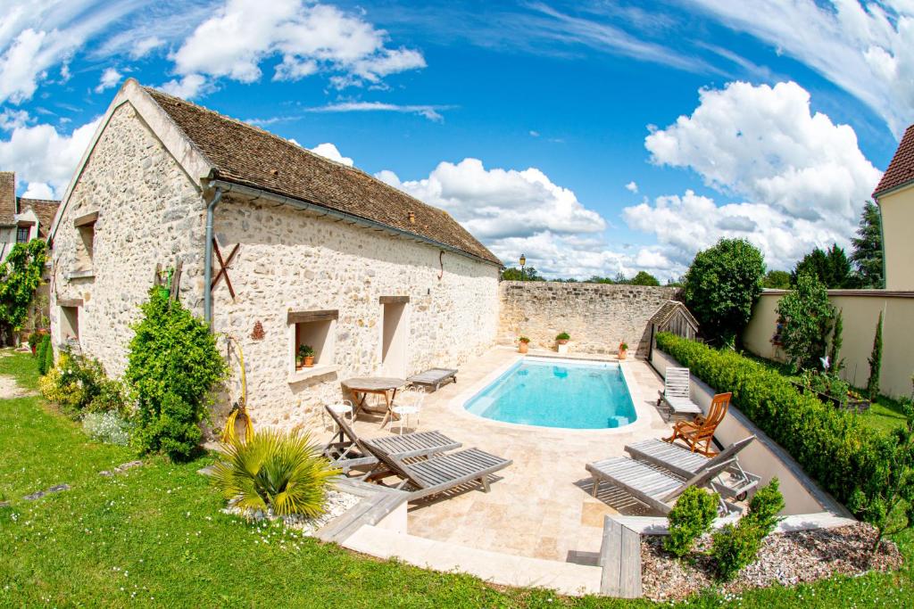 un antiguo edificio de piedra con una piscina en un patio en Casa la Rosa & Spa, en Courdimanche-sur-Essonnes