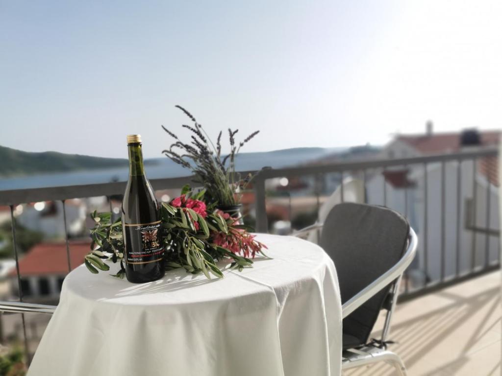Villa Ilona في بريموستين: طاولة مع زجاجتين من النبيذ والزهور على شرفة