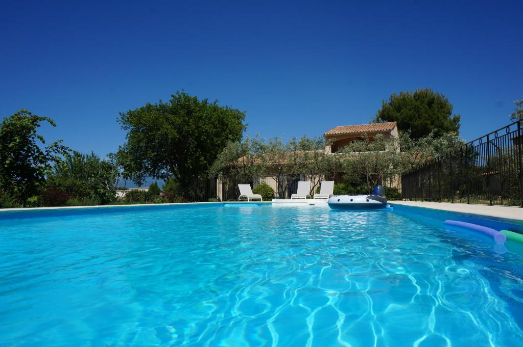 a swimming pool with a house in the background at le Gecko en Provence in La Roque-sur-Pernes