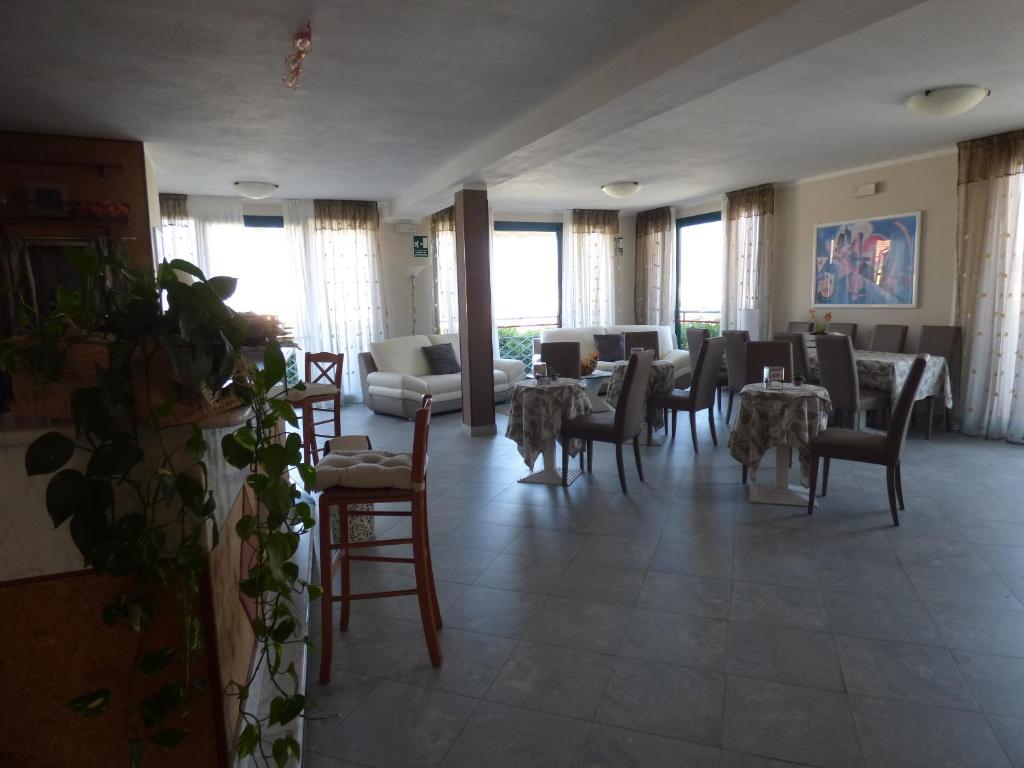 a dining room with tables and chairs and windows at Hotel Turandot in Torre del Lago Puccini