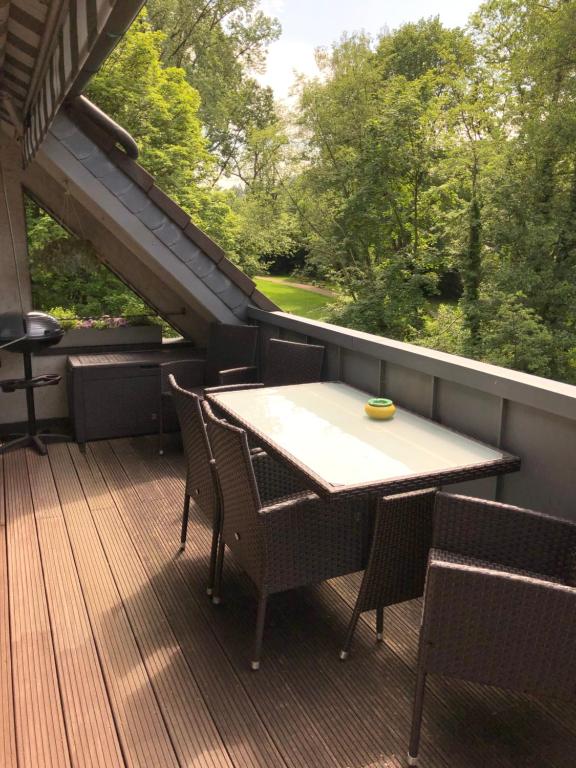 una terrazza in legno con tavolo e sedie sul balcone. di Ferienhaus "Alte Mühle" a Wiehl