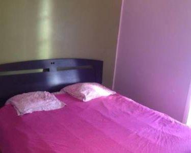 uma cama com um cobertor rosa em cima em Chambre chez l'habitant em Questembert