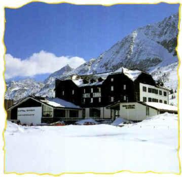 a large black building in the snow in front of a mountain at Savoia Hotel in Passo del Tonale