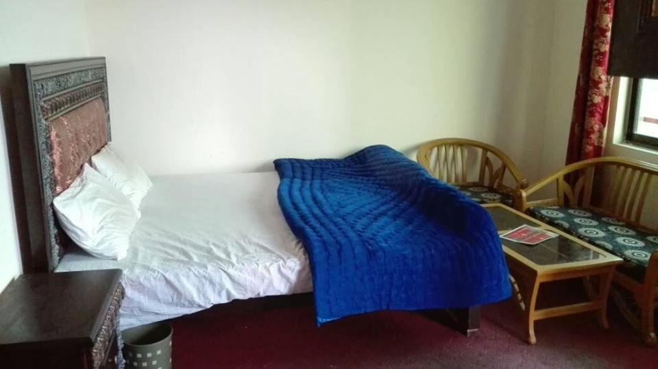 Un dormitorio con una cama con una manta azul. en Abbasi Hotel, en Murree