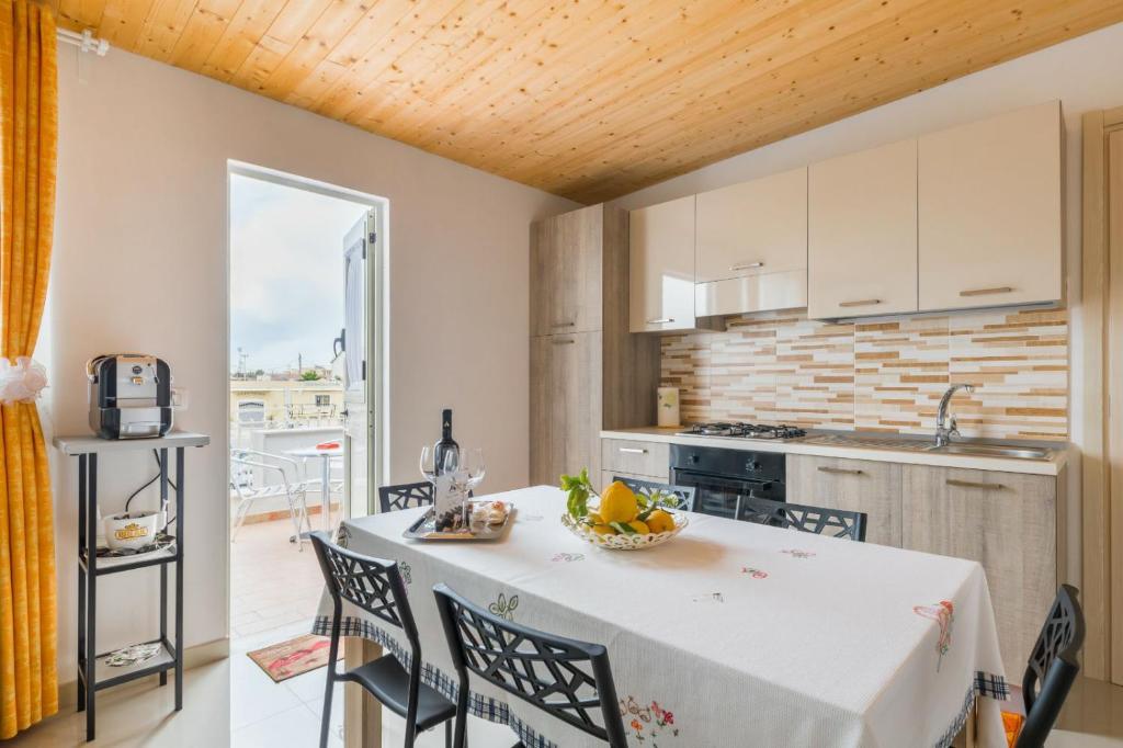 une cuisine avec une table et des chaises blanches ainsi qu'une cuisine avec un comptoir dans l'établissement Sasha's, à Avola