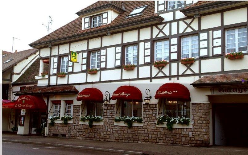 ein Gebäude mit roten Sonnenschirmen auf einer Straße in der Unterkunft Le Cheval Rouge in Louhans