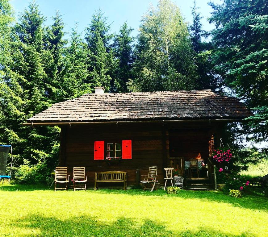 Cabaña de madera con sillas y porche con puertas rojas en Cozy Log Cabin near Faaker See, en Ledenitzen