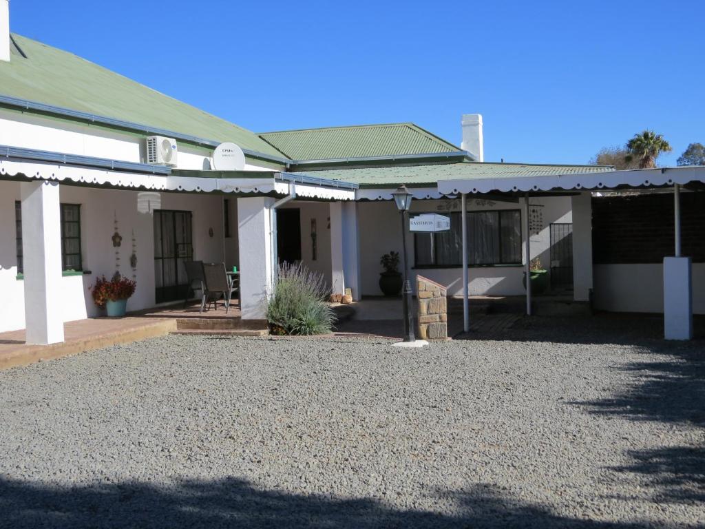 a house with a gravel driveway in front of it at Spes Bona guesthouse in Colesberg