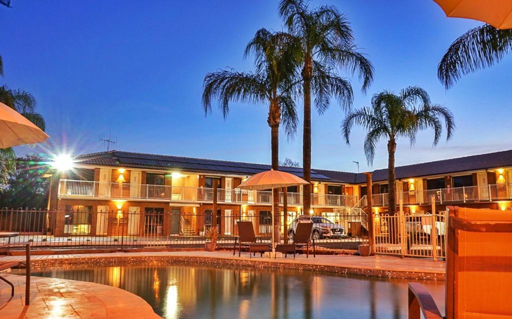 a resort with a swimming pool and palm trees at The Palms Dubbo in Dubbo