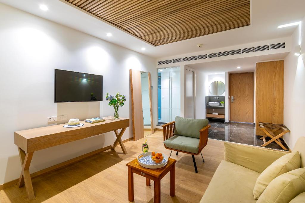 a living room with a couch and a table and a television at Limanaki Beach Hotel & Suites in Ayia Napa