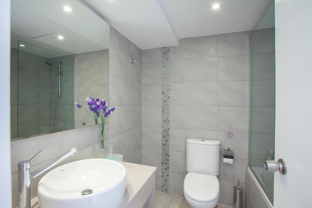 a bathroom with a white toilet and a sink at Limanaki Beach Hotel & Suites in Ayia Napa