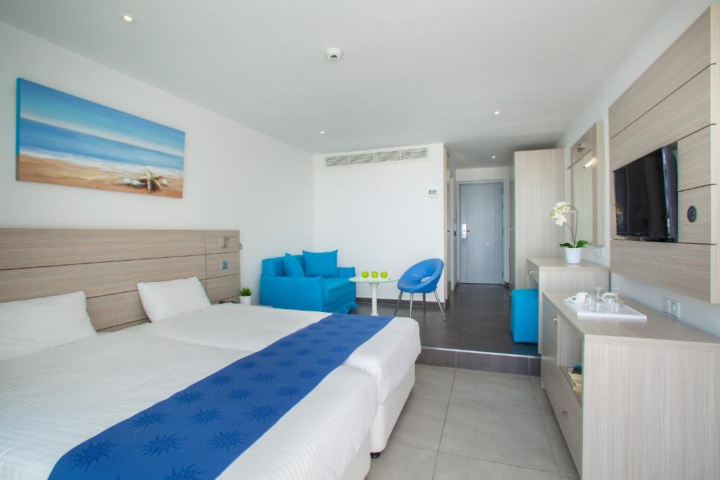 a bedroom with a large bed and a blue chair at Limanaki Beach Hotel & Suites in Ayia Napa